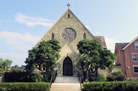 Historic church building with stone facade and large rose window, surrounded by greenery, relevant to wedding venues in Bucks/Philly Region Wedding Expo.