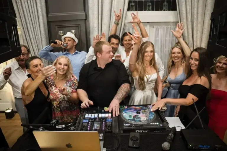 Wedding guests gathered around the FNA Events DJ booth during the reception