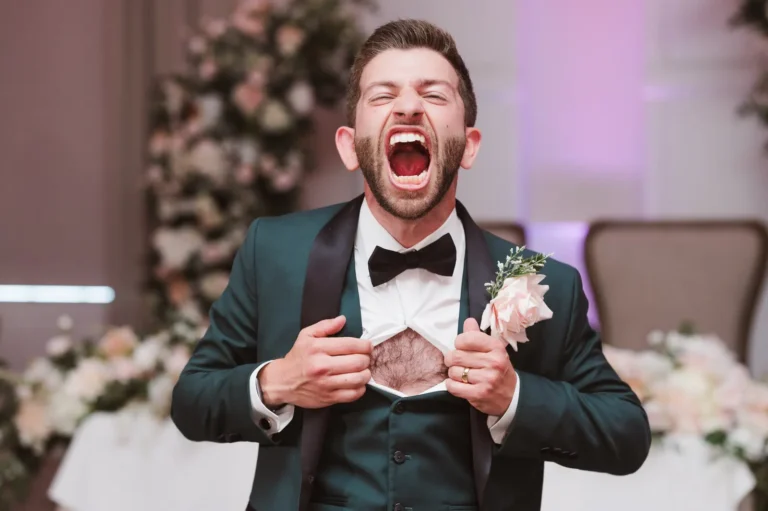 Groom in green tux with black bowtie yelling and ripping off a white button-down at the chest like superman