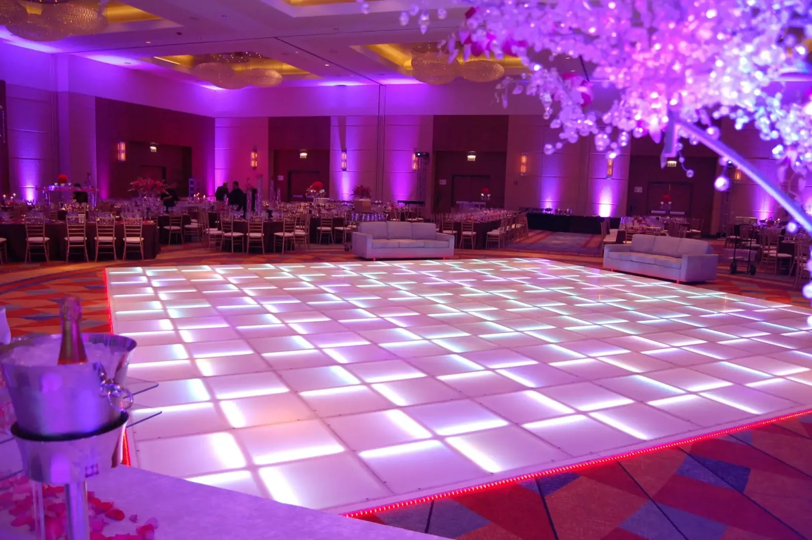 Ballroom with purple uplighting and a lit dance floor by FNA Events