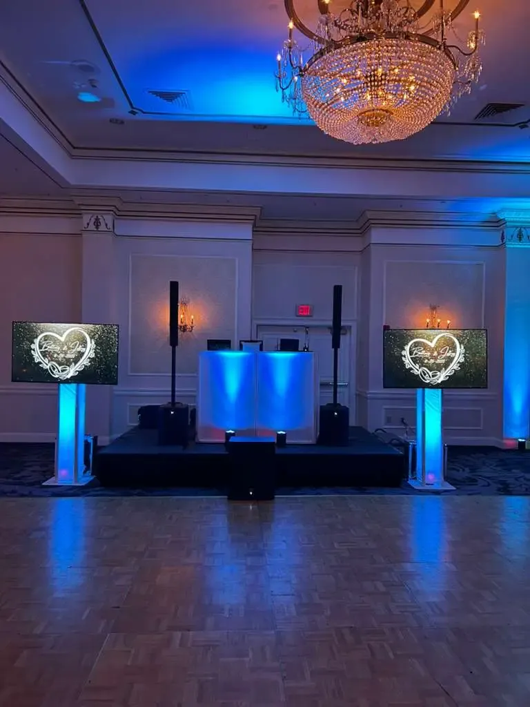 FNA DJ setup with blue uplighting and monogram screens, Fresh New Angle Events