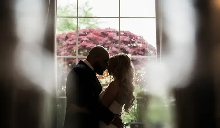 Bride and groom kissing in soft window light, photographed by the FNA photography team